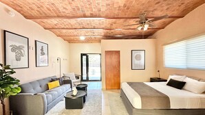 A modern bedroom with a bed, a sofa, a coffee table, and a ceiling fan. - Studio With Salt Water Pool (Chapala)