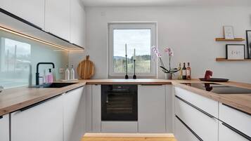A modern kitchen with a built-in oven, a window with a view, and a wooden countertop.