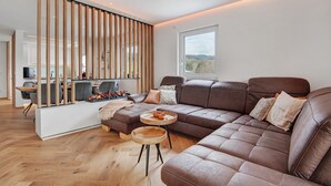 Un saló modern amb un sofà modular, un moble d'aprisar de fusta i una zona de menjador.