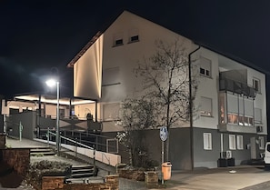 Un bâtiment doté d’un escalier menant à une entrée abritée, d’une poubelle et d’un lampadaire.