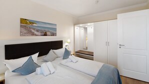 Une chambre d’hôtel avec un lit, des oreillers, un tableau, une table de chevet, une lampe et une armoire.