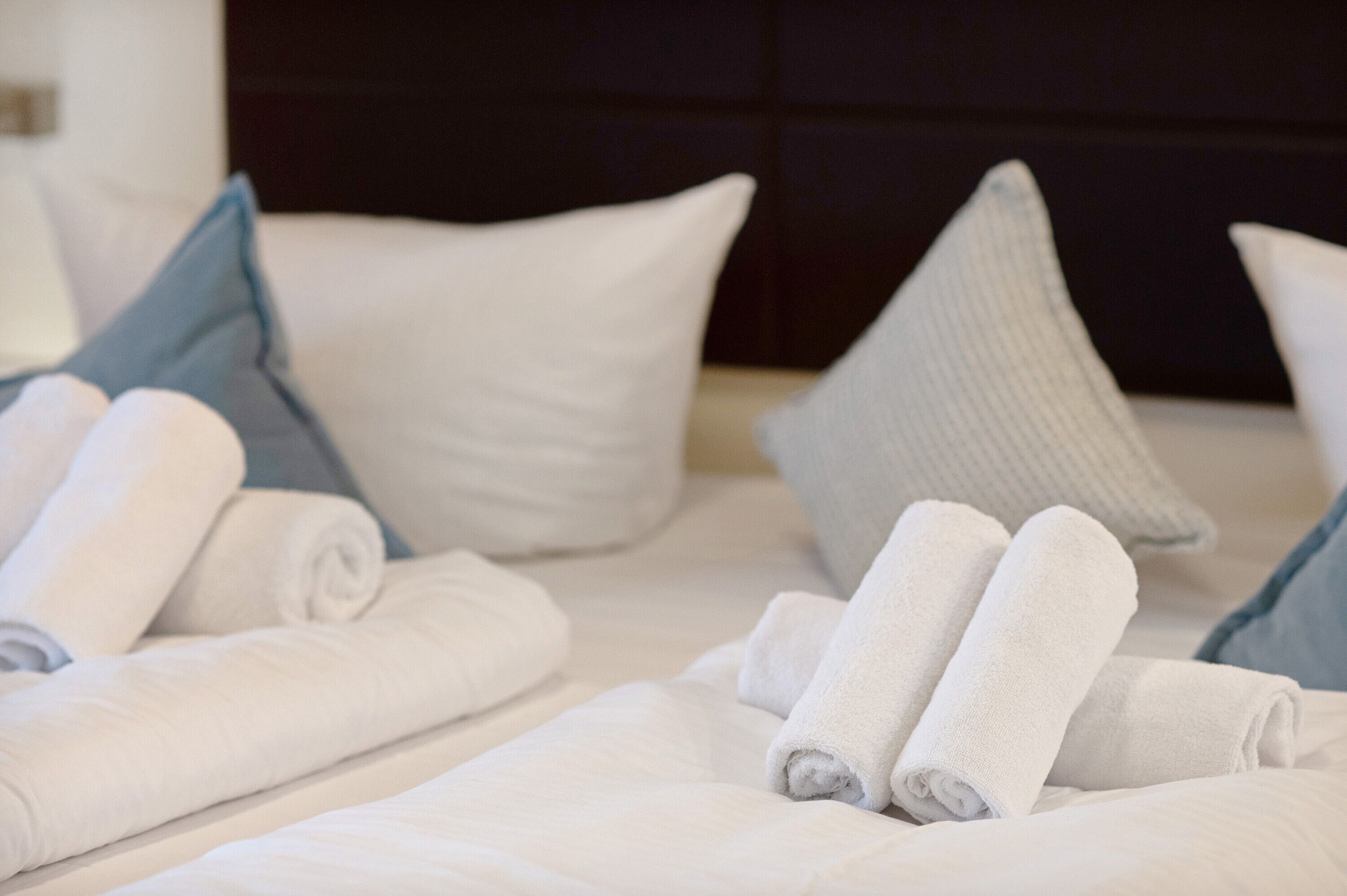 A neatly made bed with rolled white towels and pillows in a hotel room.
