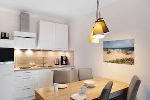 A modern kitchen with white cabinets, a coffee maker, and a dining area with a table and chairs.