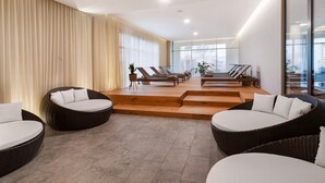 Un salon moderne avec des meubles en osier, un escalier et de grandes fenêtres.