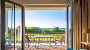 Un balcon avec une table et des chaises, une vue sur la verdure et un paysage lointain.