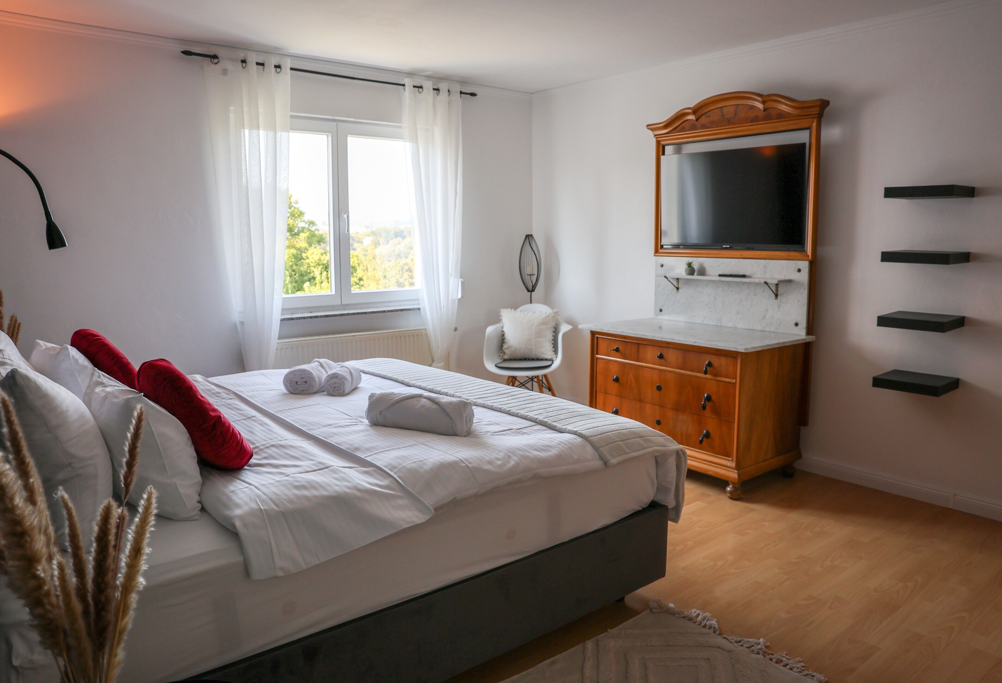 A bedroom with a bed, a dresser, a mirror, and a window.