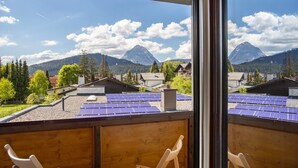 Un balcon équipé de panneaux solaires, avec vue sur la montagne, et deux chaises.