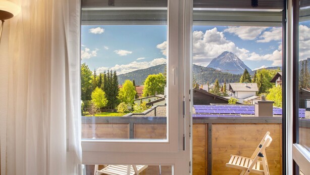 Un balcon avec vue sur une montagne, des meubles en bois et un mur en bois.