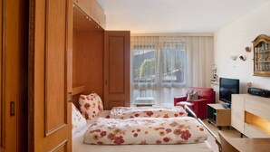 Une chambre d’hôtel avec deux lits, une télévision, un bureau et une fenêtre avec des rideaux.