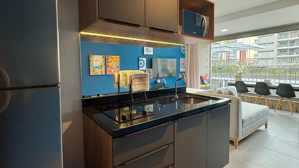 A modern kitchen with a central island, built-in appliances, and a view of the city through large windows. - Apartamentos Prime-Prox a Oscar Freire (São Paulo)