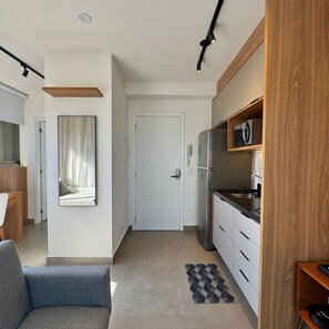 Une cuisine moderne équipée d’un réfrigérateur, d’un four à micro-ondes et de meubles de rangement en bois. On y trouve également un coin repas avec une chaise et une table.