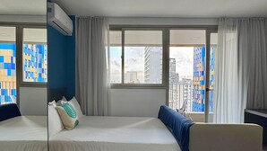 A hotel room with a bed, a sofa, a window with curtains, and a view of buildings. - Apartamentos Prime-Prox a Oscar Freire (São Paulo)