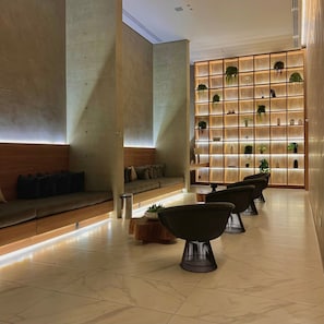 En moderne lobby med siddeområde, en væg dækket af planter og et pænt flisegulv.