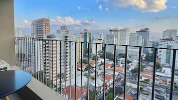 Un balcón con vistas a un paisaje urbano, que incluye edificios altos y un cielo despejado.