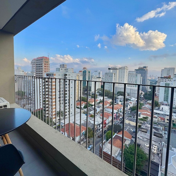 A balcony with a view of a cityscape, including high-rise buildings and a clear sky.