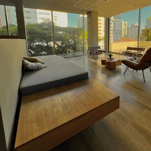 A modern living room with a built-in sofa, a wooden coffee table, and a view of the city through large windows. - Apartamentos Prime-Prox a Oscar Freire (São Paulo)