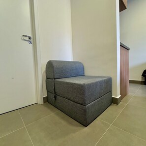 A small, grey, upholstered seating area in a hallway with a white door and a wooden panel on the right. - Apartamentos Prime-Prox a Oscar Freire (São Paulo)