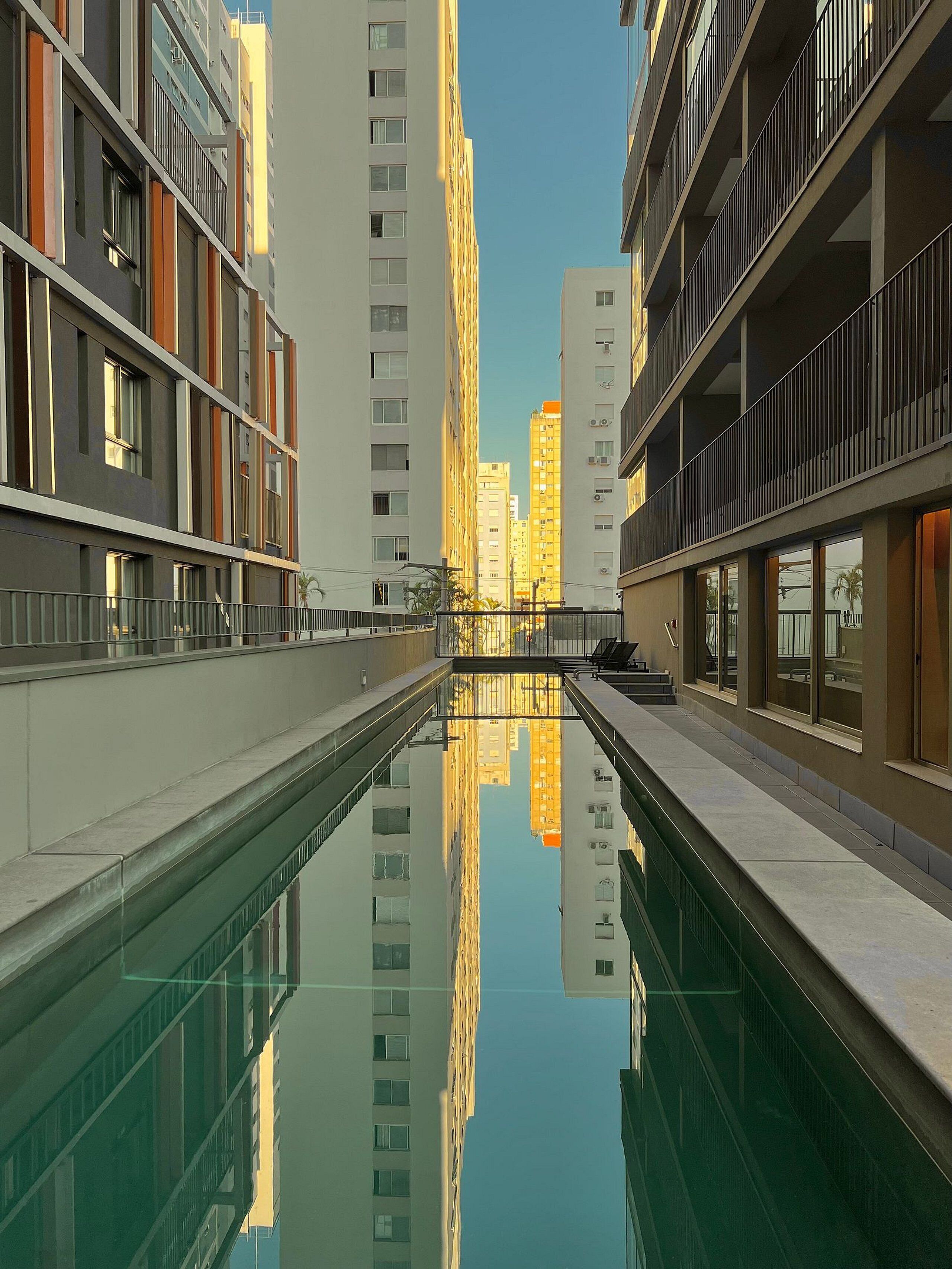 A modern building with a reflective pool in the foreground, surrounded by high-rise structures.
