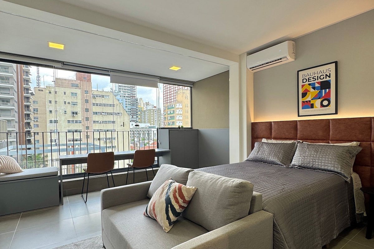 Ett modernt hotellrum med en stor säng, en soffa, ett skrivbord och utsikt över stadsbilden.