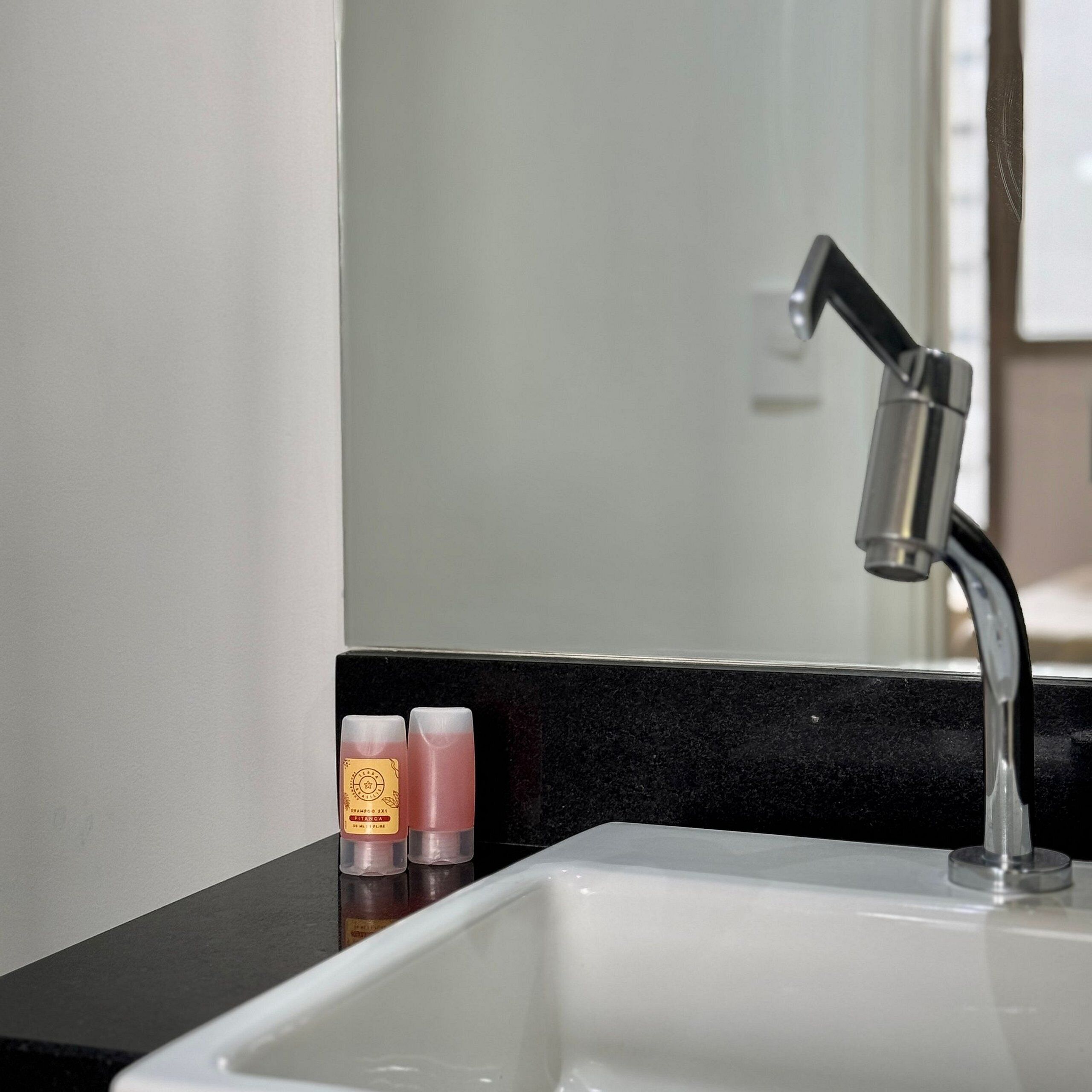 Un lavabo de salle de bain avec un plan de toilette noir et un miroir au-dessus.