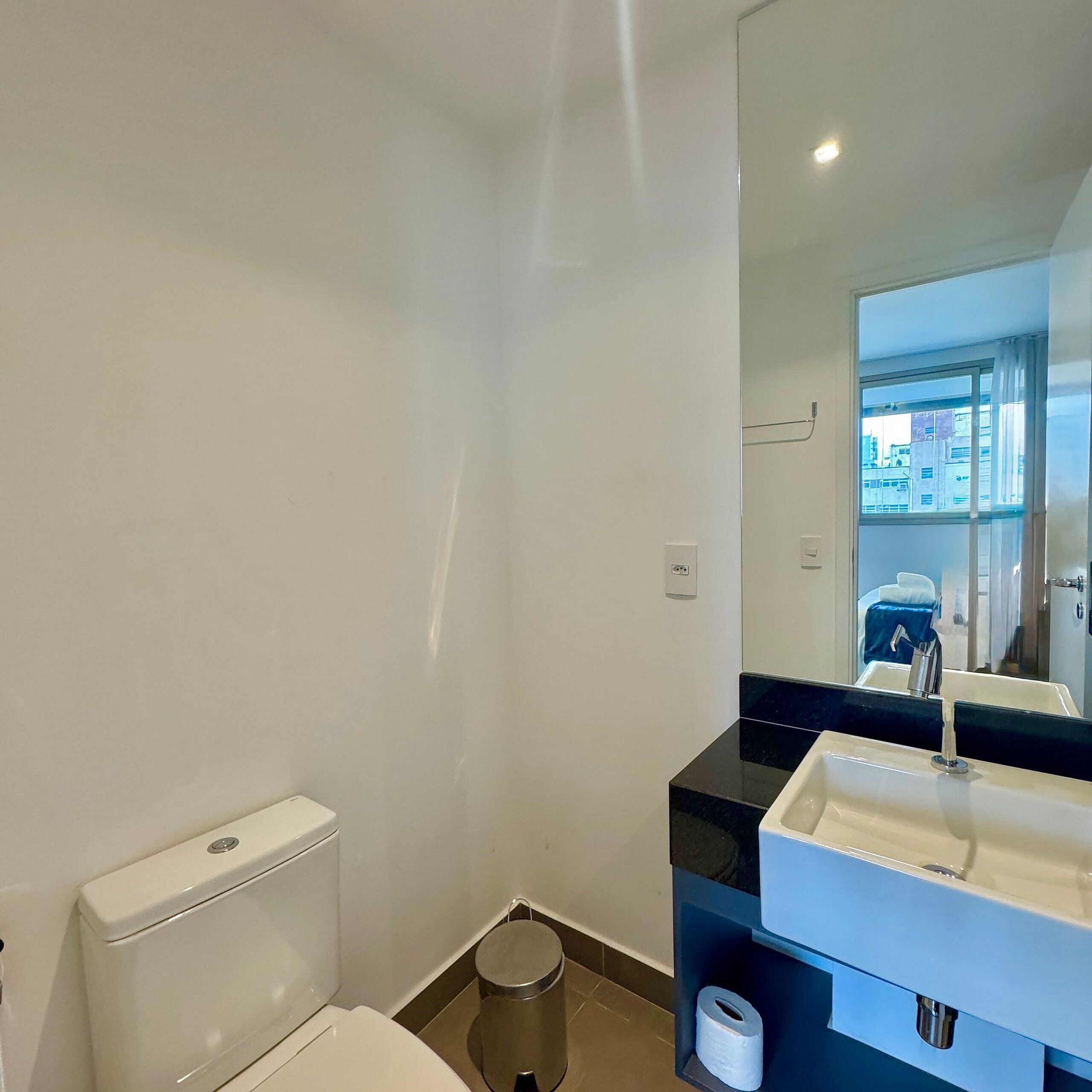 A modern bathroom with a toilet, sink, and mirror.