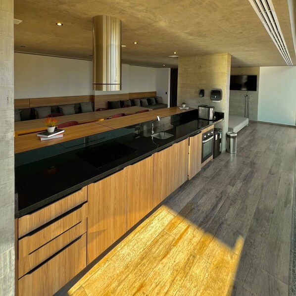 A modern kitchen with a wooden countertop, stainless steel appliances, and a built-in oven. - Apartamentos Prime-Prox a Oscar Freire (São Paulo)