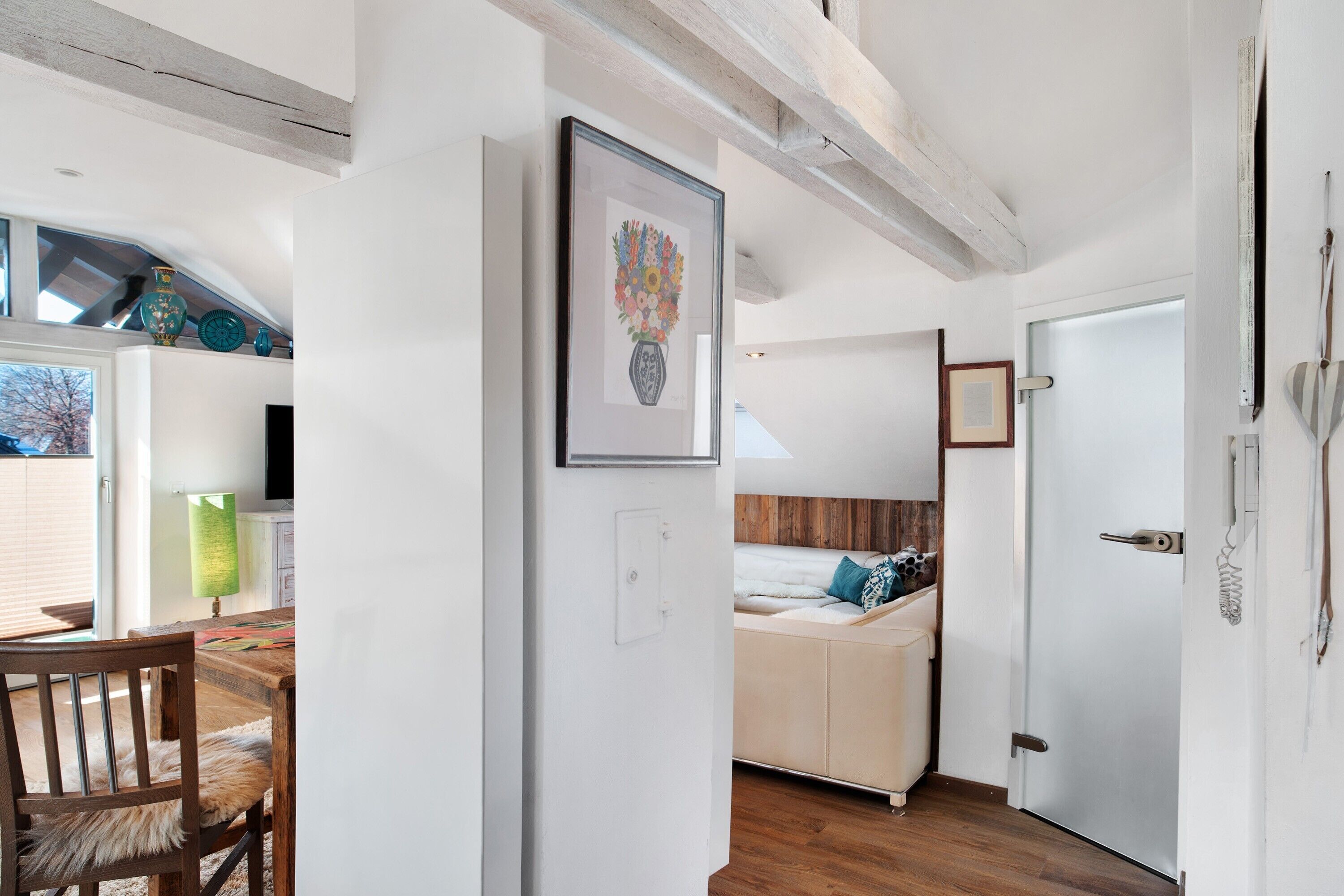 A room with a bed, a chair, a table, and a door.