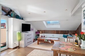 A modern living room with a television, sofa, coffee table, and a skylight.