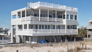 Ein mehrstöckiges Gebäude direkt am Strand mit Balkonen und einem sandigen Strand im Vordergrund.