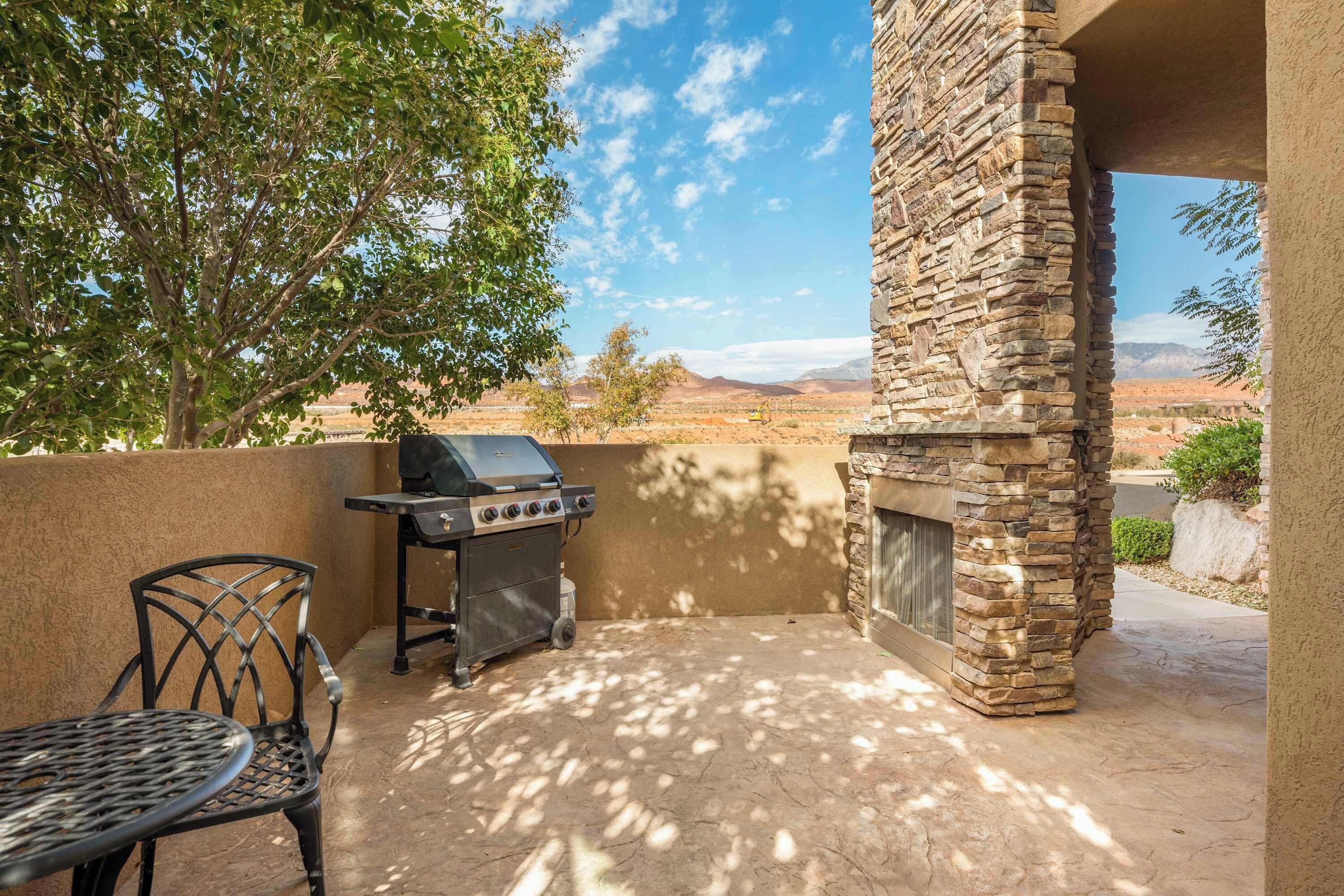 Un patio al aire libre con una chimenea de piedra, una parrilla y una mesa y silla de metal.