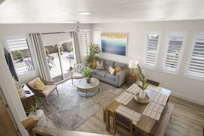 A spacious living area with a grey sofa, round coffee table, and dining table set with placemats.