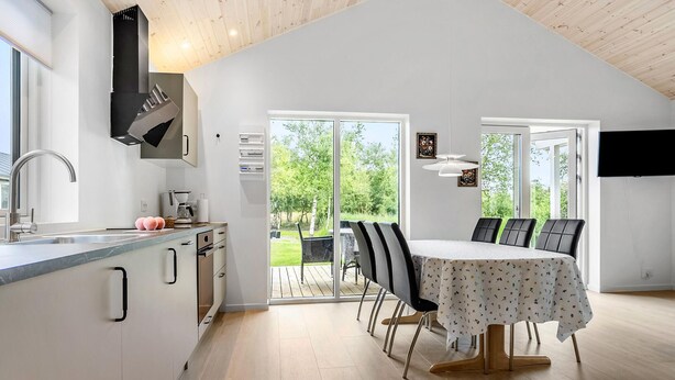 Eine moderne Küche mit Essbereich, großen Fenstern und Blick ins Freie.