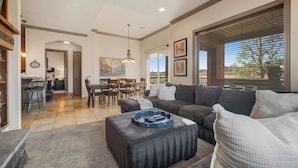 A spacious living room with a large sectional sofa, a coffee table, and a dining area with a table and chairs. - Coral Sunset – Amenity-Filled! (Hurricane)
