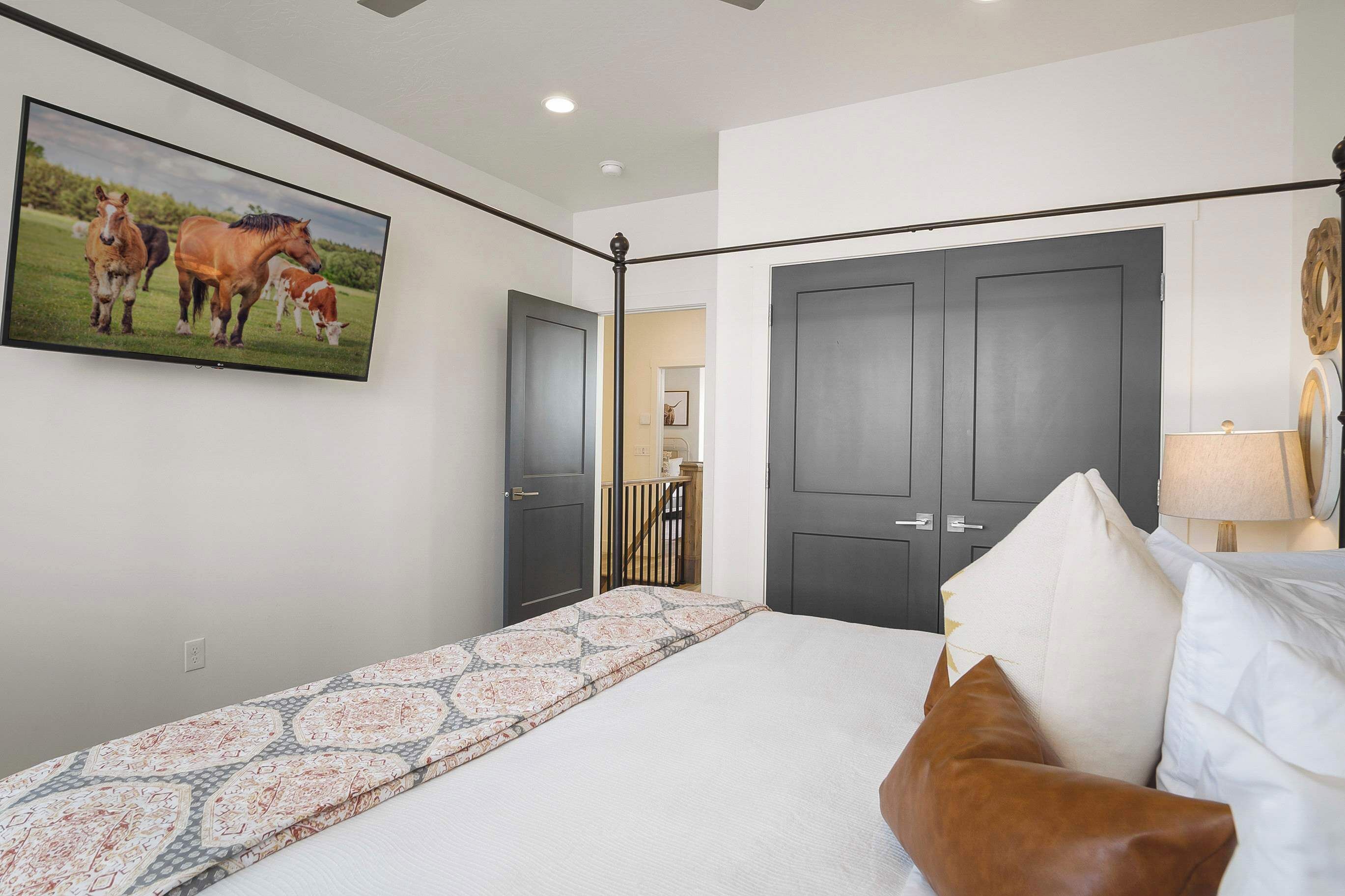 A bedroom with a bed, a large painting of horses, and a wardrobe.