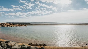 A calm lake with a sandy beach and rocky shoreline. - Sunset Oasis | Desert & Mtn Views (Hurricane)