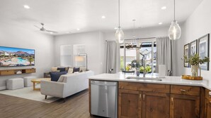 A modern kitchen with wooden cabinets, a dishwasher, and pendant lights.