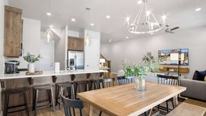 A modern kitchen with a wooden island, bar stools, and pendant lighting.