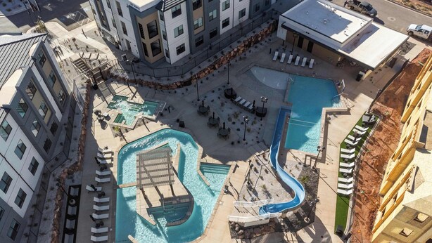 An aerial view of a hotel with a central swimming pool, multiple lounge areas, and a parking lot. - Sweet Retreat | Rest & Relax Near National Parks (Hurricane)