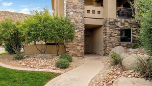 A modern building with a stone facade, a balcony, and a landscaped garden with a pathway leading to the entrance. - Sweet Retreat | Rest & Relax Near National Parks (Hurricane)