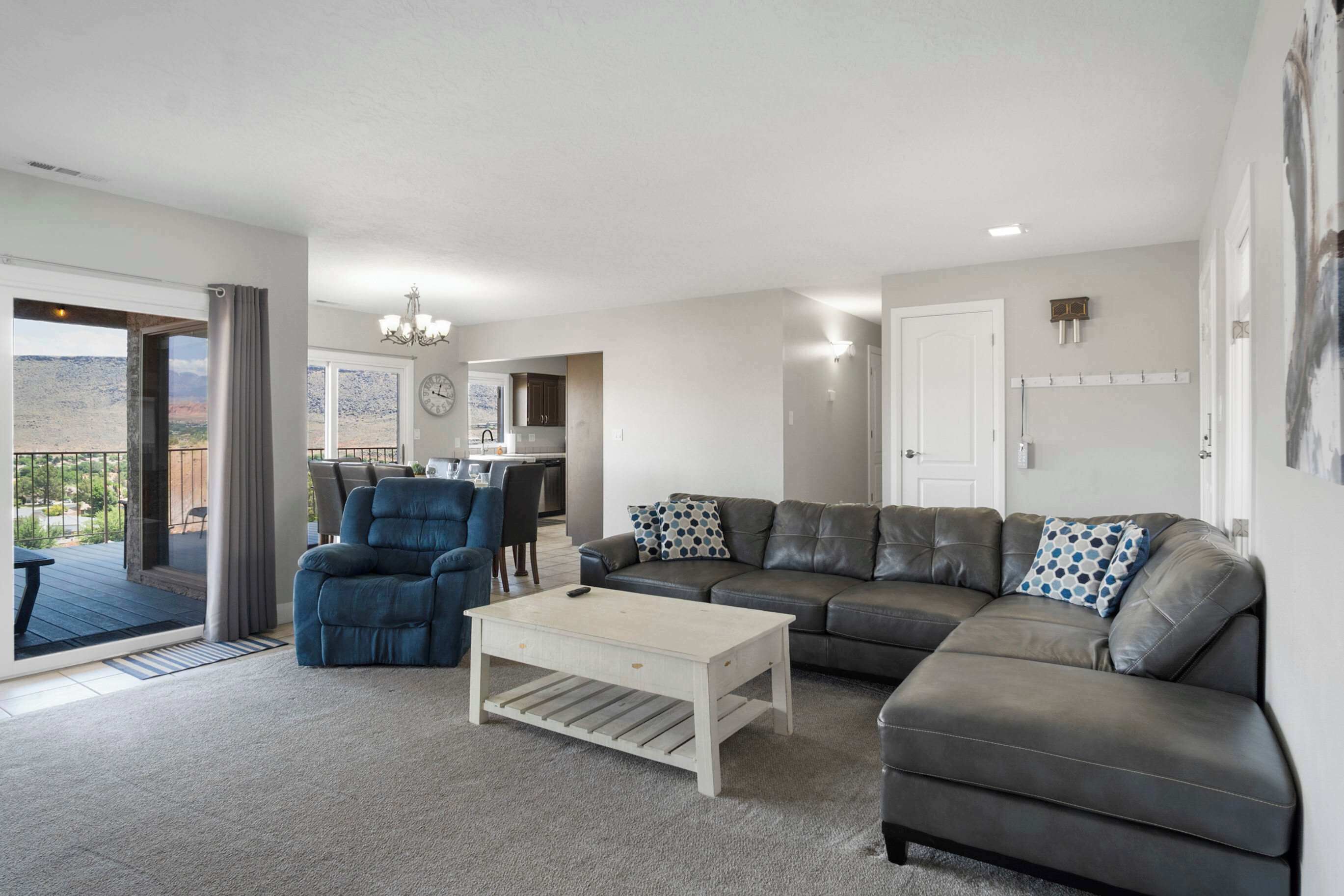 A modern living room with a sectional sofa, a blue armchair, and a white coffee table.