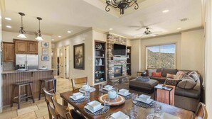 A spacious kitchen with wooden cabinets, a dining area with a large table set for six, and a cozy living room with a fireplace. - Desert Ocean Vibes- Resort Amenities (Hurricane)