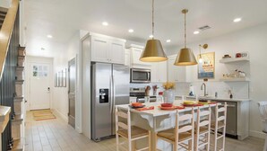 Una cocina moderna con armarios blancos, electrodomésticos de acero inoxidable y una isla central con sillas.