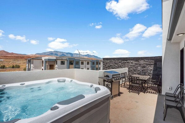 Ein Whirlpool mit Blick auf die Berge, Gartenmöbel und eine Steinmauer.