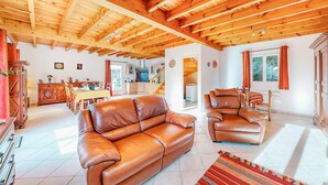 A spacious living room with a wooden ceiling, leather sofas, and a dining area with a table and chairs. - 2 bedroom gorgeous home in Louvie-Soubiron (Louvie-Soubiron)