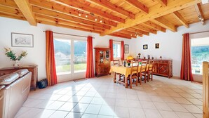 A spacious dining area with a wooden ceiling, a large window with curtains, and a view of the outdoors. - 2 bedroom gorgeous home in Louvie-Soubiron (Louvie-Soubiron)