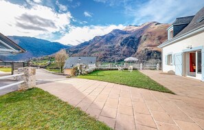 Un cortile con lastricato, un piccolo prato e vista sulle montagne.