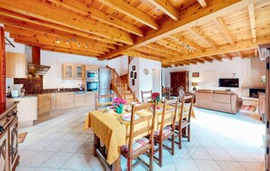 A spacious kitchen with wooden beams, a dining area with a table set for four, and a living area with a sofa and TV. - 2 bedroom gorgeous home in Louvie-Soubiron (Louvie-Soubiron)