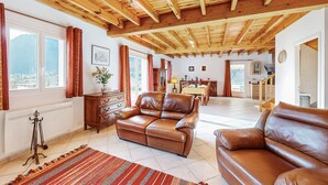 A spacious living room with a high wooden ceiling, leather sofas, a dining area, and a view through large windows. - 2 bedroom gorgeous home in Louvie-Soubiron (Louvie-Soubiron)