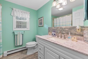 A bathroom with a white toilet, a sink with a marble countertop, and a shower curtain.