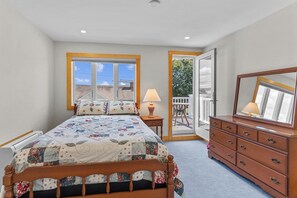 A bedroom with a bed, dresser, and a window with a view.